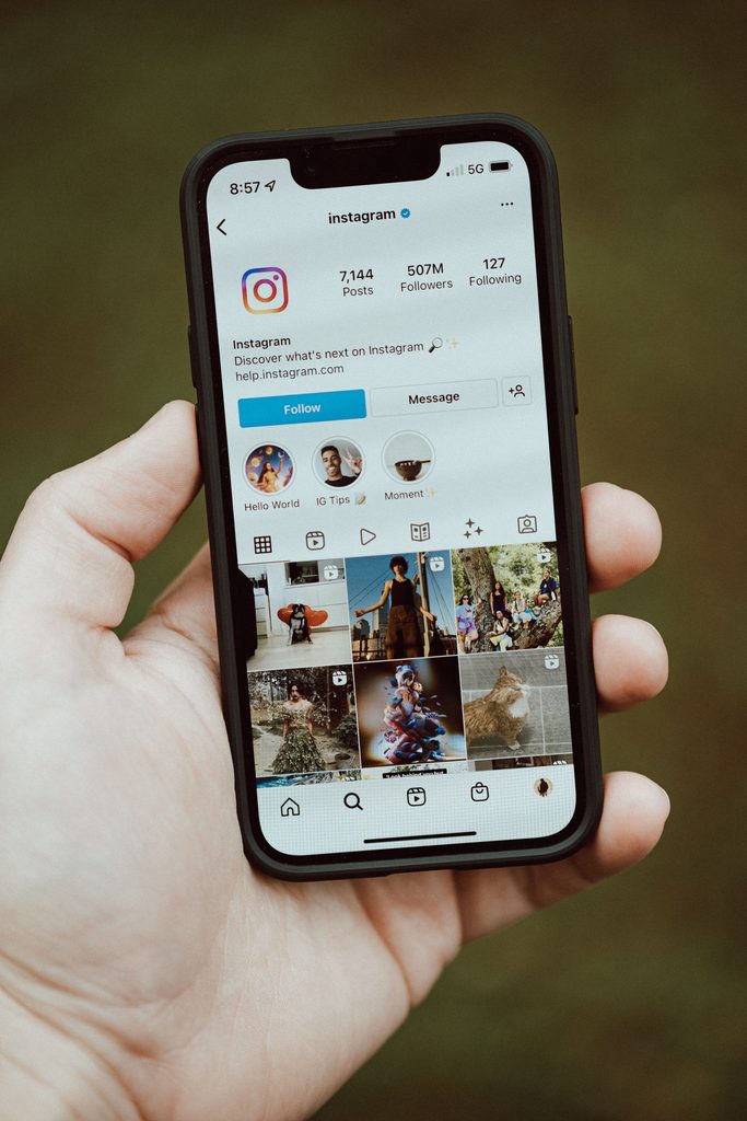 Hand holding a smartphone showing Instagram's official profile page with 507M followers.
