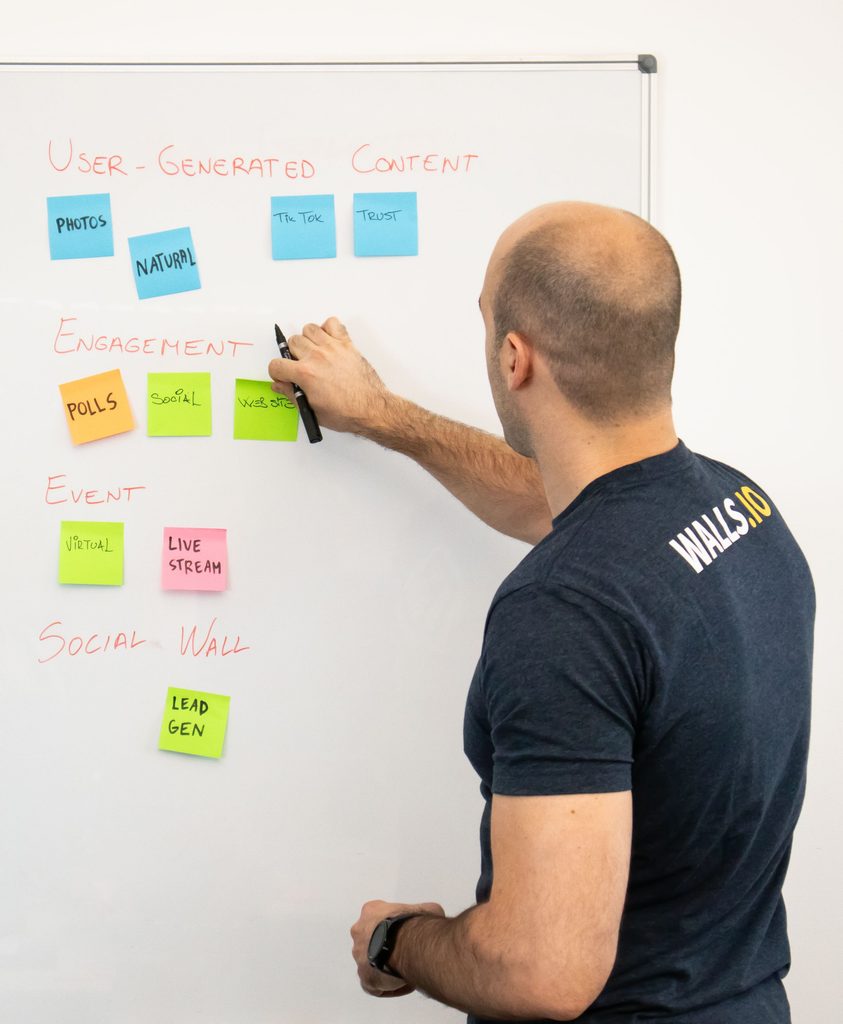 Marketer adding sticky notes about user-generated content, engagement, and lead-gen to a whiteboard.